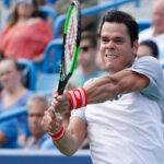 milos raonic returns serve in quarterfinal action against novak djokovic