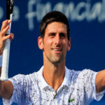 novak djokovic raises his arms in celebration as he walks to the net to shake hands after defeating marin cilic at the western & southern open