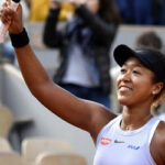 naomi osaka raises her racket to the crowds in attendance at the french open after defeating anna karolina schmiedlova