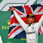 British F1 driver Lewis Hamilton raises the Union flag on the podium while celebrating winning his sixth british grand prix title as teammate Valtteri Bottas appluads