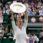 simona halep raises her trophy in celebration after defeating serena williams in the women's finals at wimbledon.