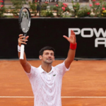 Novak Djokovic raises his arms to acknowledge fans after winning his semifinal match against casper rudd on sunday at the italian open.